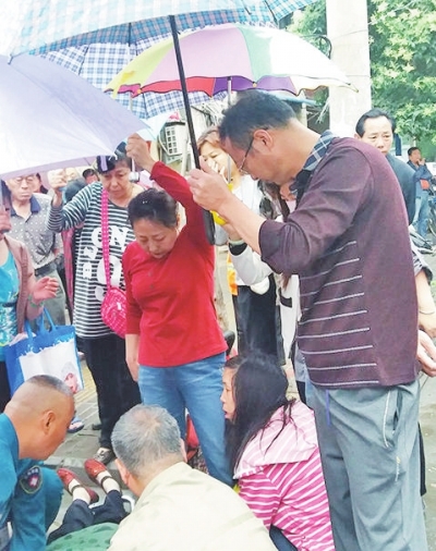  老人突发疾病倒地 十余路人撑伞搭起
