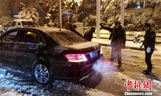 凌晨，雪中车子趴窝的车主向城管求助。杨钦云 摄