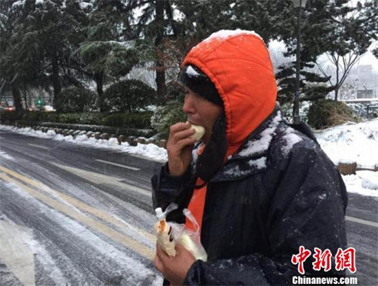 奋战了一夜的环卫工人到早上才能休息一下，吃口热乎乎的包子，暖暖手脚。贾红刚 摄