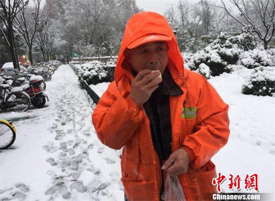 奋战了一夜的环卫工人到早上才能休息一下，吃口热乎乎的包子，暖暖手脚。贾红刚 摄