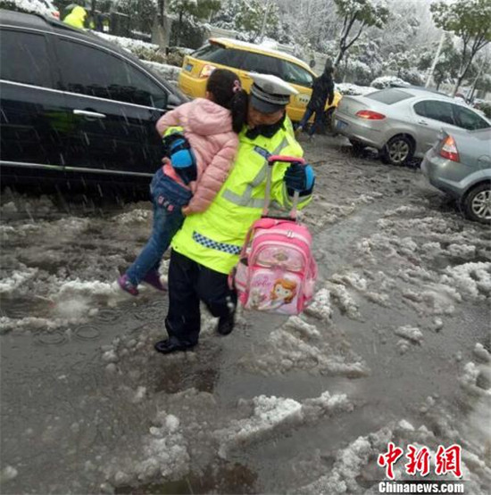 被交警叔叔“举高高”跨过雪水、抱进学校的孩子们。南京交警供图 摄