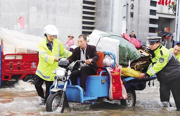 暴雨突袭 云南宣威城民警背老人过马路